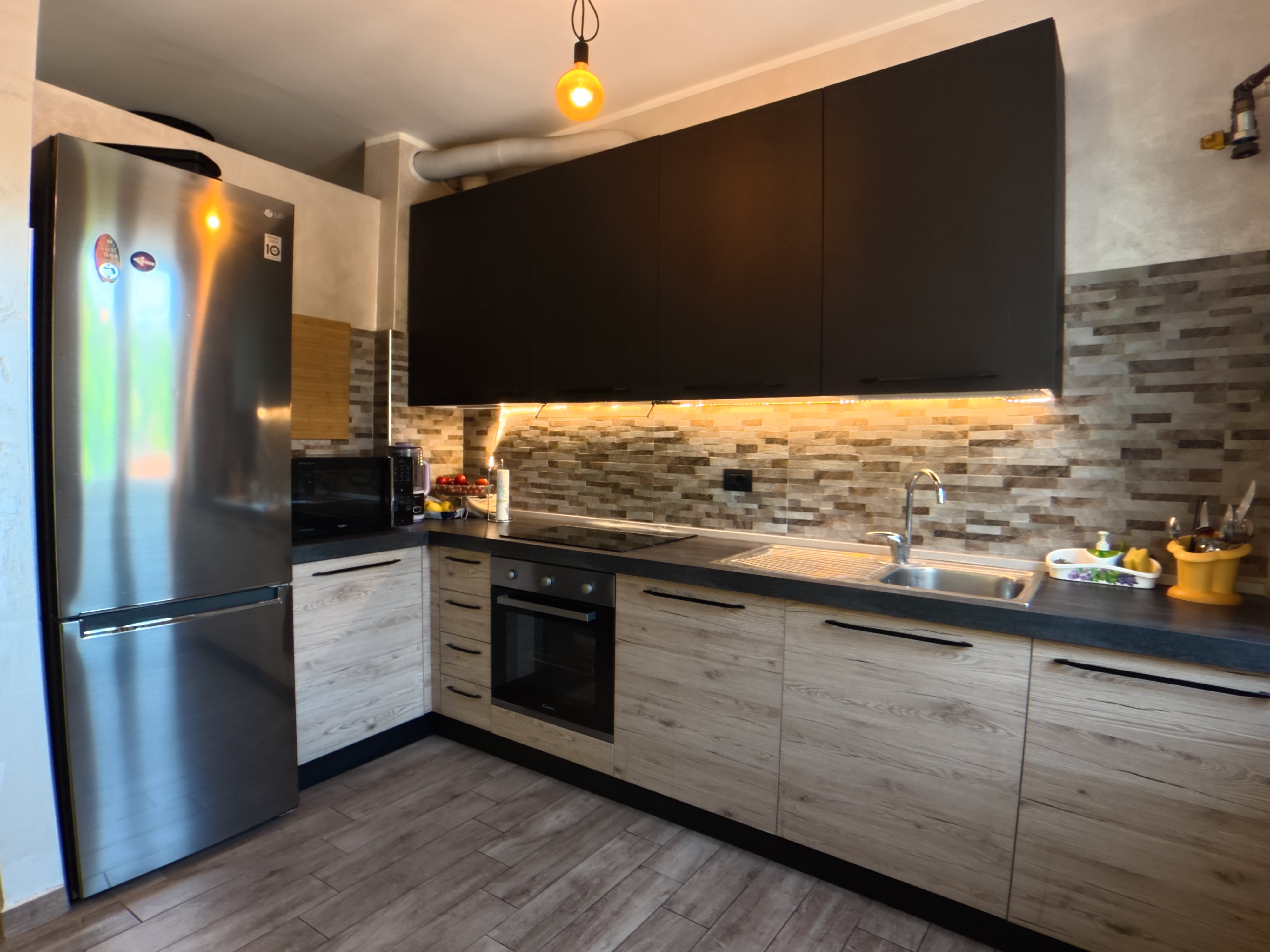 Cucina a vista con elettrodomestici in acciaio e piano cottura a induzione
