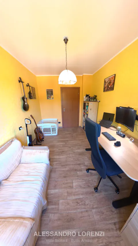 Studio arredato con chitarre a parete, scrivania e divano letto
